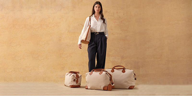 The Tusting Como Collection of Explorer Luggage, set next to a beautify, dark blue Aston Martin car